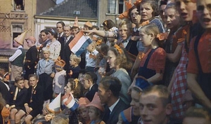 Children wearing orange ribbons and waving Dutch flags